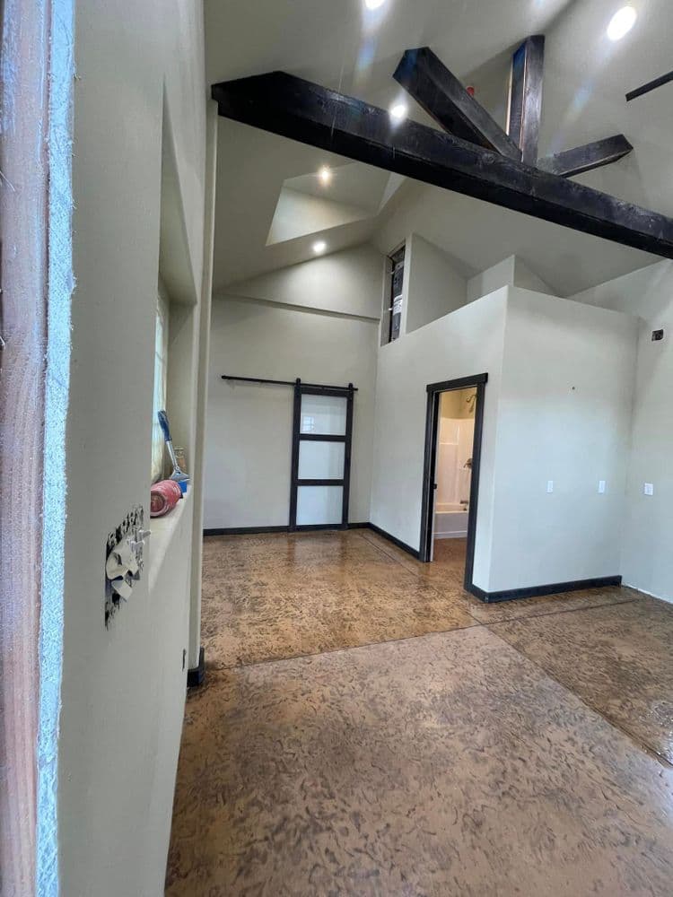 Modern interior of a spacious room with high ceilings and wooden beams, featuring a sliding door.