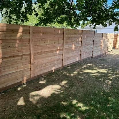 Modern wooden privacy fence in a landscaped yard providing outdoor privacy and aesthetics.